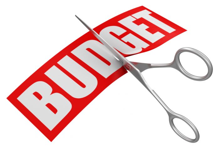 The word budget being cut in half with scissors